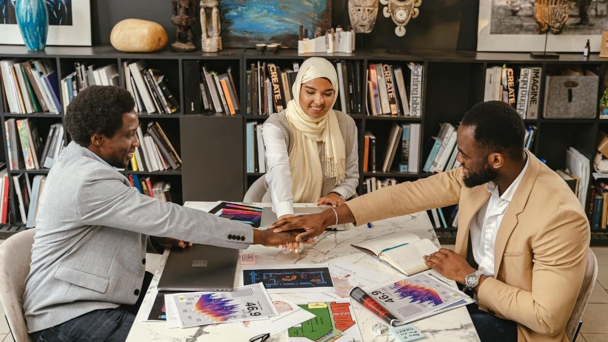 Three professionals in an office setting engage in team collaboration, fostering innovation and cooperation.