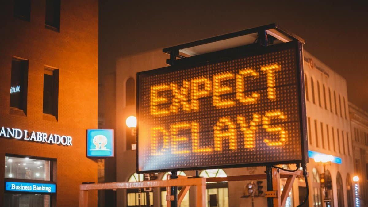 Mobile electronic traffic sign with inscription Expect delays placed on road in city street in evening time