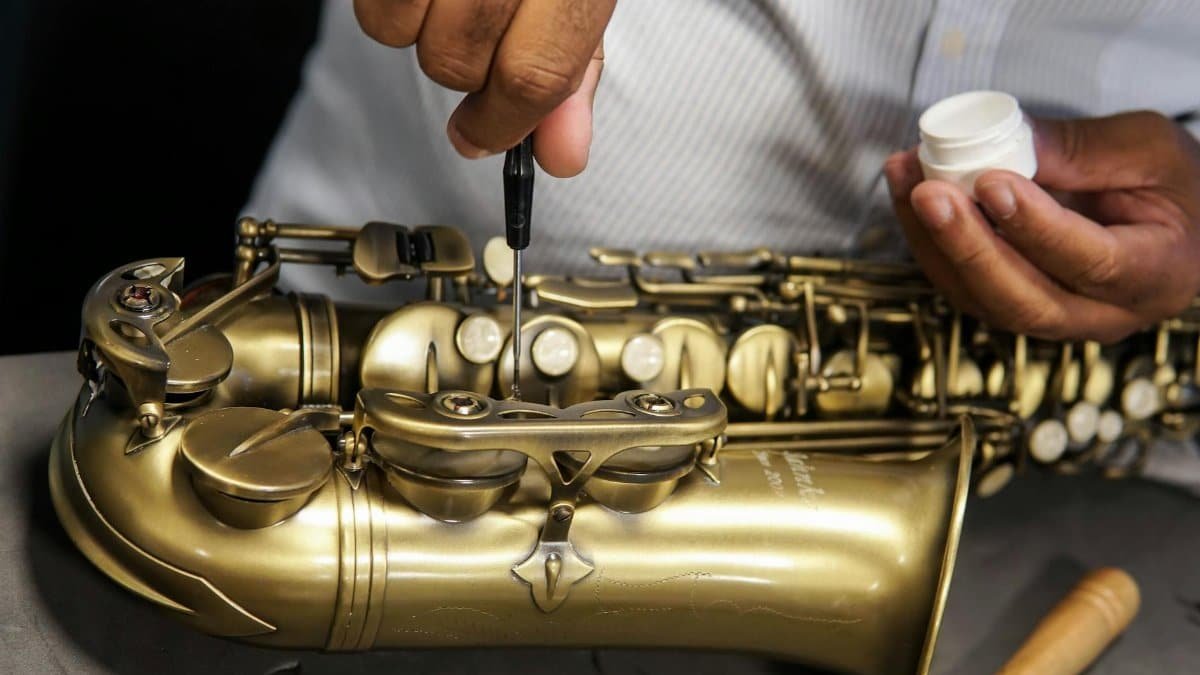 A skilled technician repairing a saxophone, showcasing craftsmanship and expertise in musical instrument maintenance.