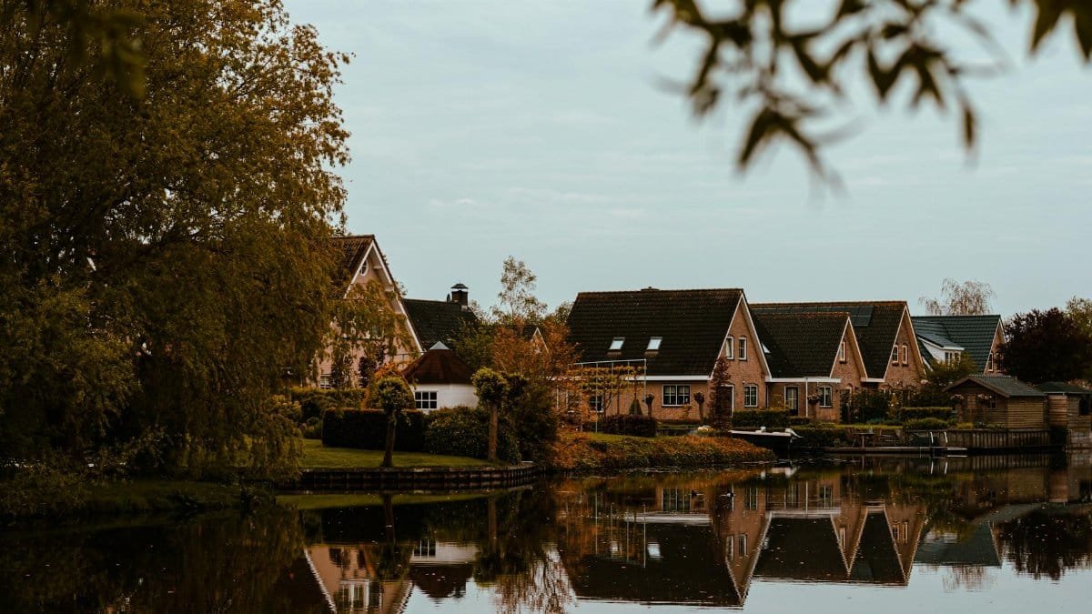 Picturesque residential area in the Netherlands with charming homes reflected in a tranquil lake during autumn.