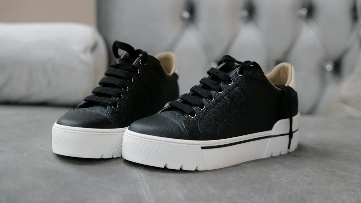 Close-up of elegant black leather sneakers on a plush surface, showcasing luxury fashion.