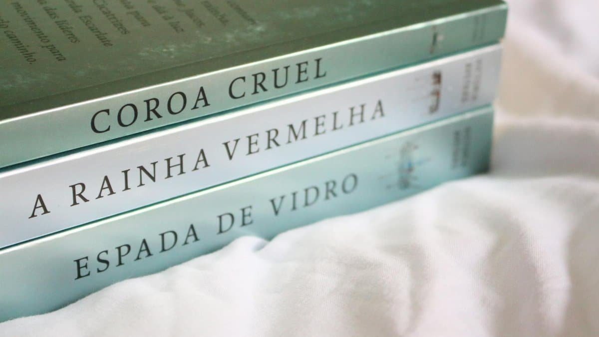 Three novels with Portuguese titles neatly stacked on a soft white background.