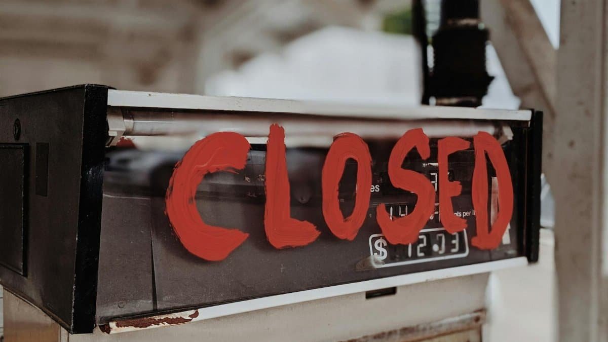 A red 'CLOSED' sign painted on an old gas pump at an outdoor station.