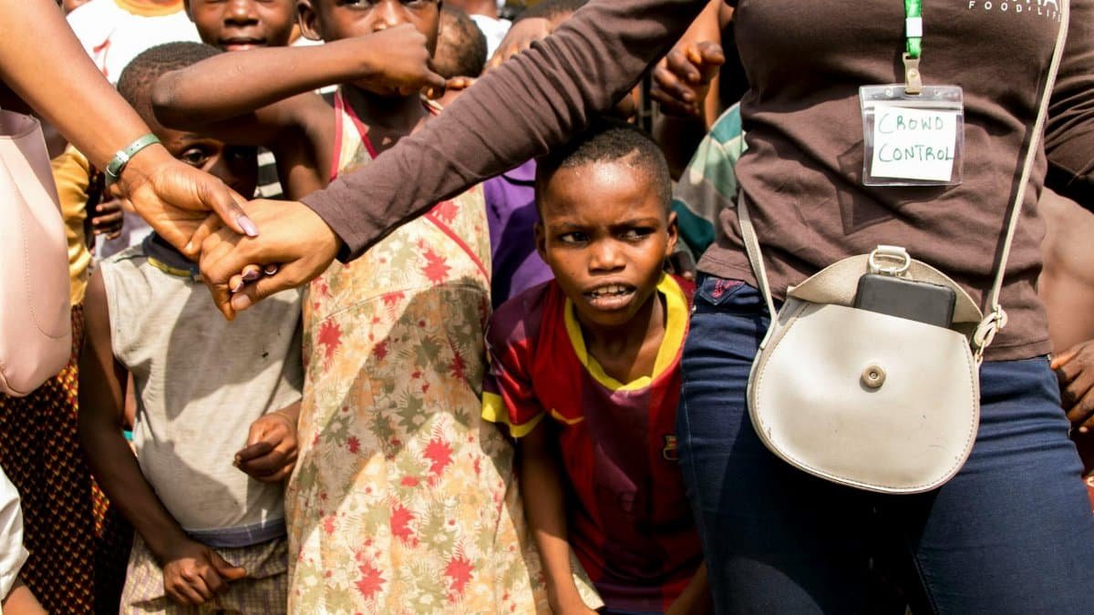 Children gathered with security personnel at a community event, promoting safety.
