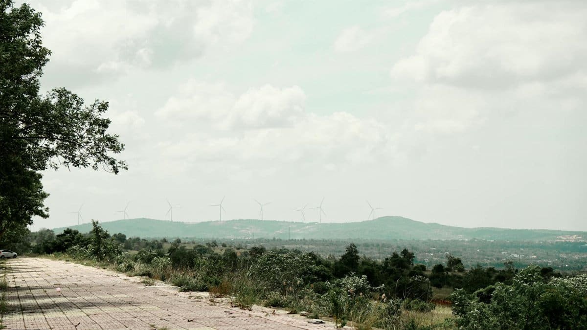 A picturesque landscape of wind turbines spread across a hilly region under a cloudy sky.