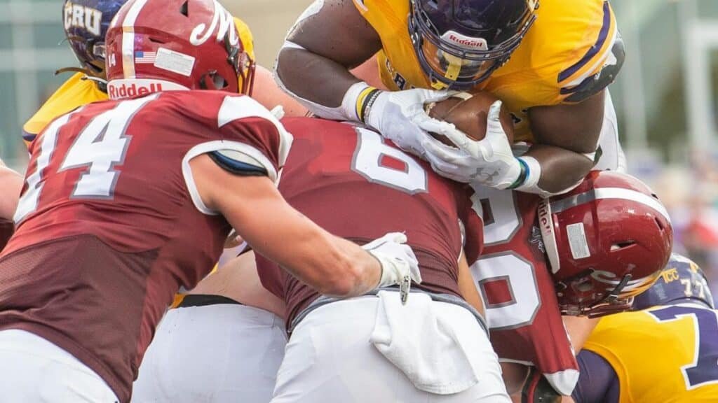 A dynamic scene of American football players in a mid-game tackle during a competitive match.