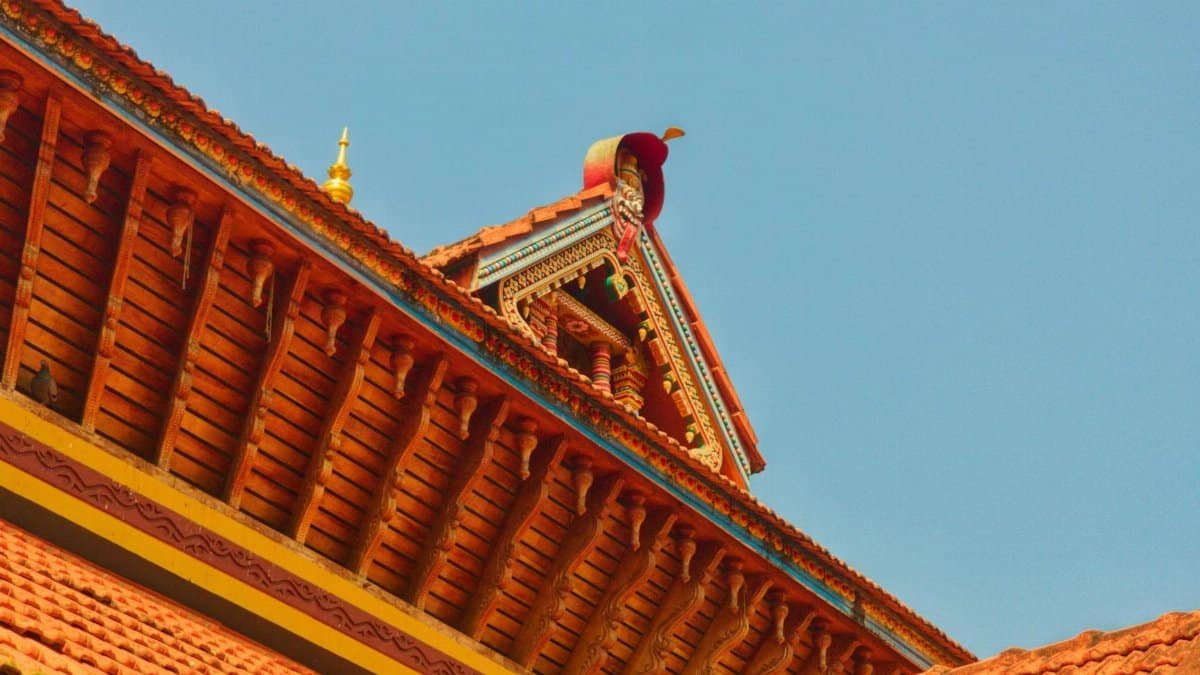 Close-up view of an intricate traditional temple roof with a clear blue sky backdrop.