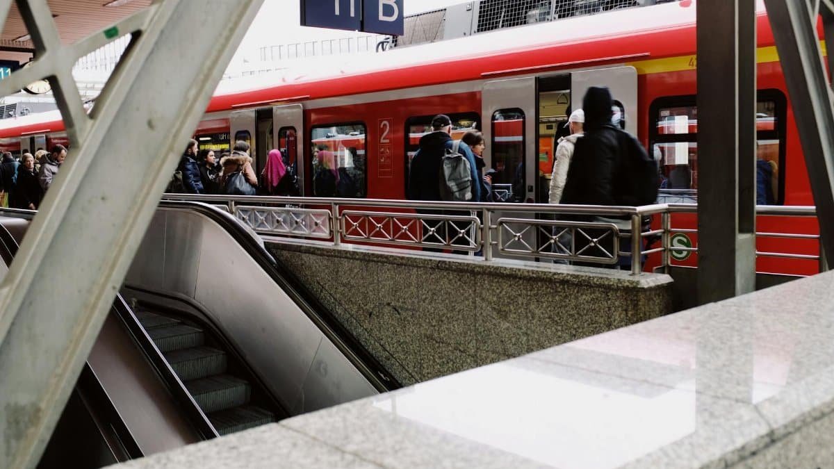 City commuters boarding a red train at a bustling urban station platform. Captured with a modern style.