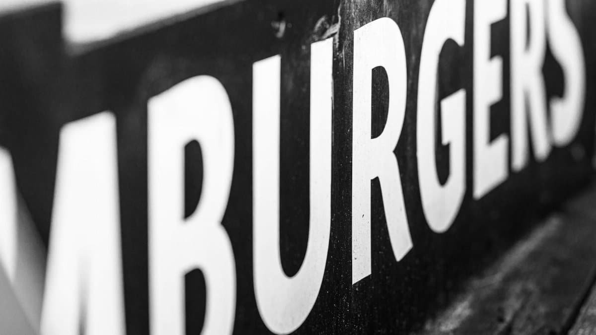 Monochrome close-up of a hamburgers sign, highlighting texture and typography.