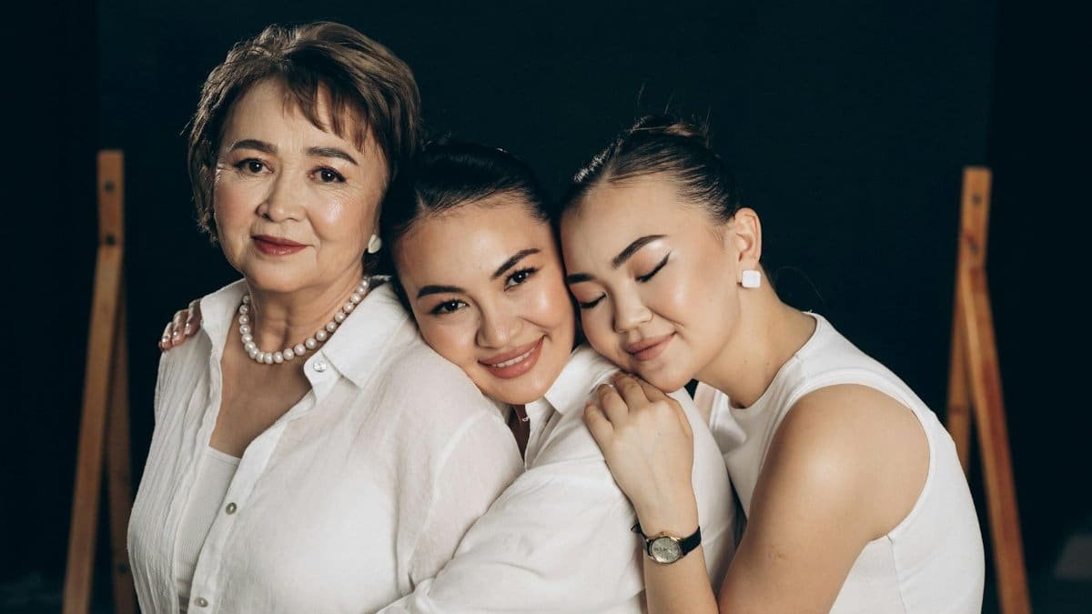 Three women of different generations sharing a warm embrace and smile, symbolizing family love.
