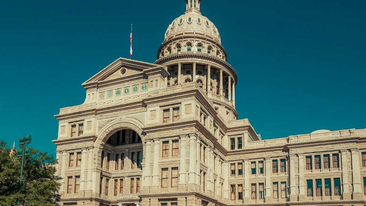 Low angle shot of the historical Texas State Capitol building under a clear blue sky in Austin, TX.