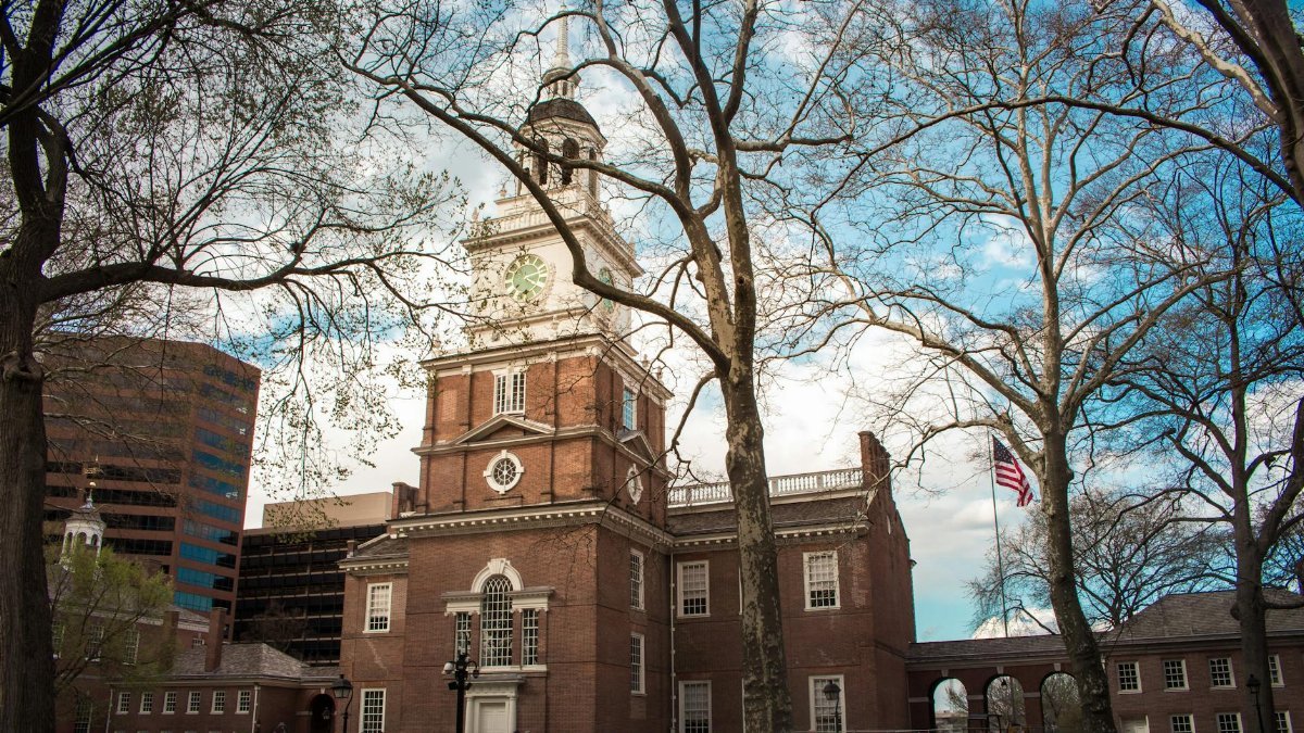 Independence Hall in Philadelphia with a vibrant blue sky and surrounding trees in spring.