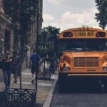 A school bus parked on a city street with pedestrians and a SEPTA bus in Philadelphia.