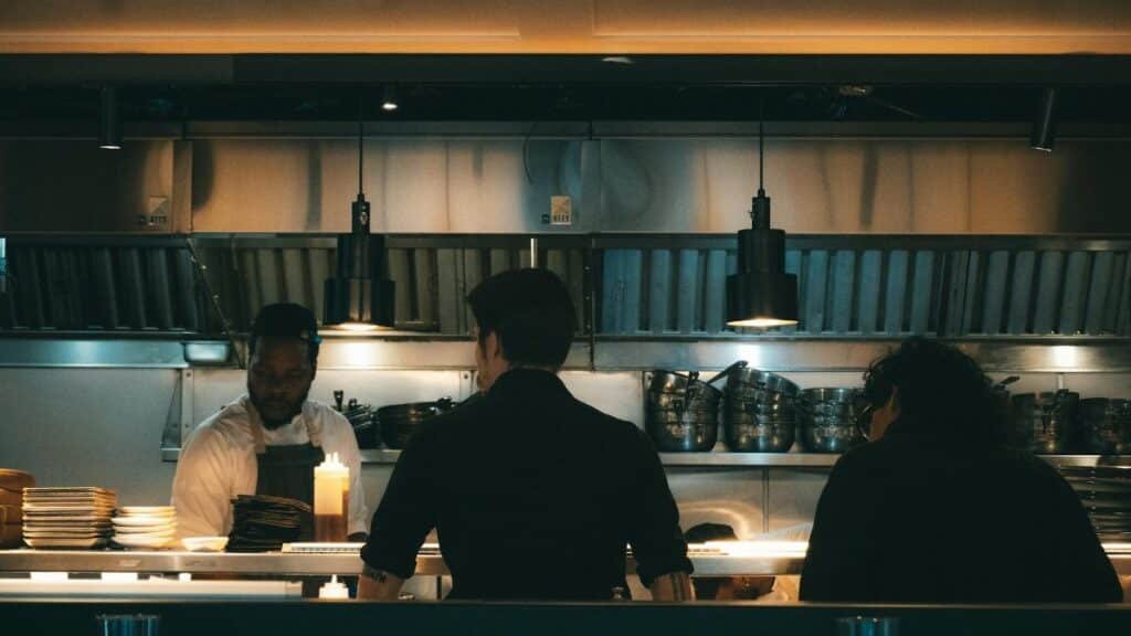 Chefs working in a bustling New York kitchen, evening scene.
