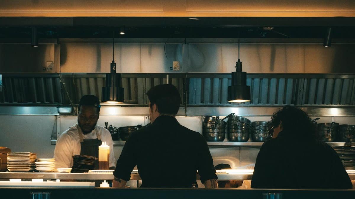 Chefs working in a bustling New York kitchen, evening scene.