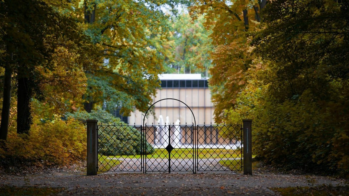 Beautiful gated entrance to a garden surrounded by vibrant autumn trees.