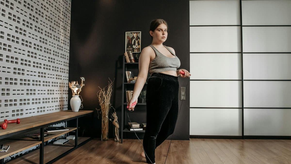A woman performs a jump rope workout at home, focusing on fitness and health.