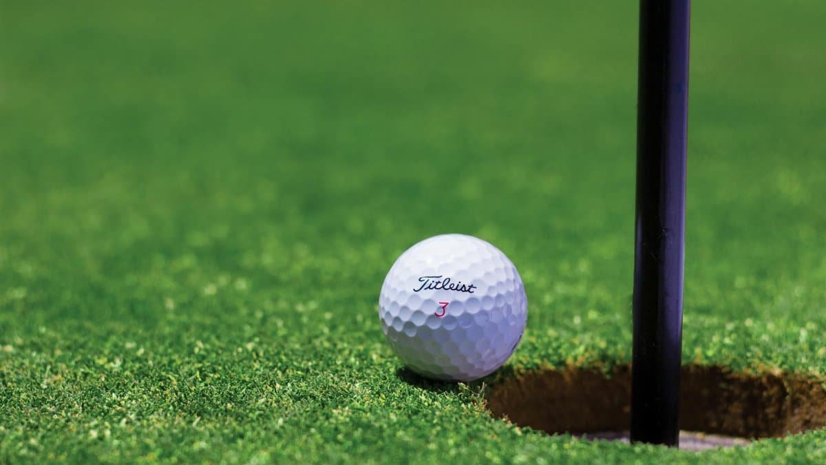 Close-up of a golf ball near a hole on a vibrant golf green, capturing the moment of near success.