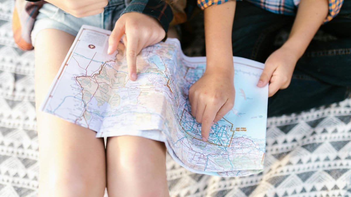 Two children point to a location on a map, planning a fun outdoor adventure.