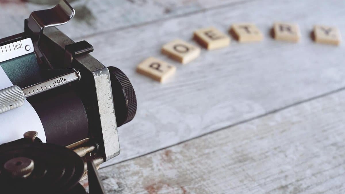 Close-up of a vintage typewriter with the word 'Poetry' spelled out on Scrabble tiles.