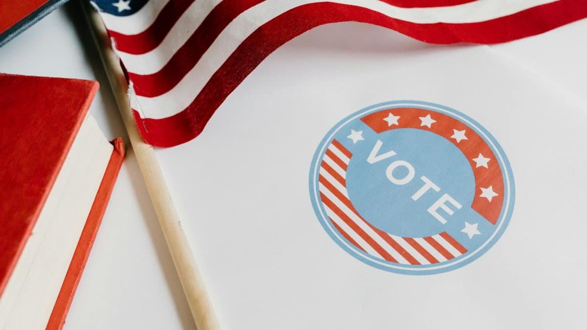 Patriotic image with American flag and vote symbol on paper.