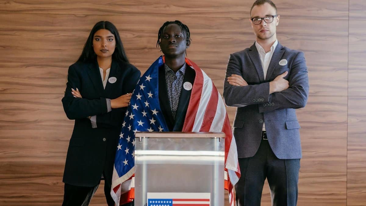 Diverse group of political candidates standing with American flag at voting podium.