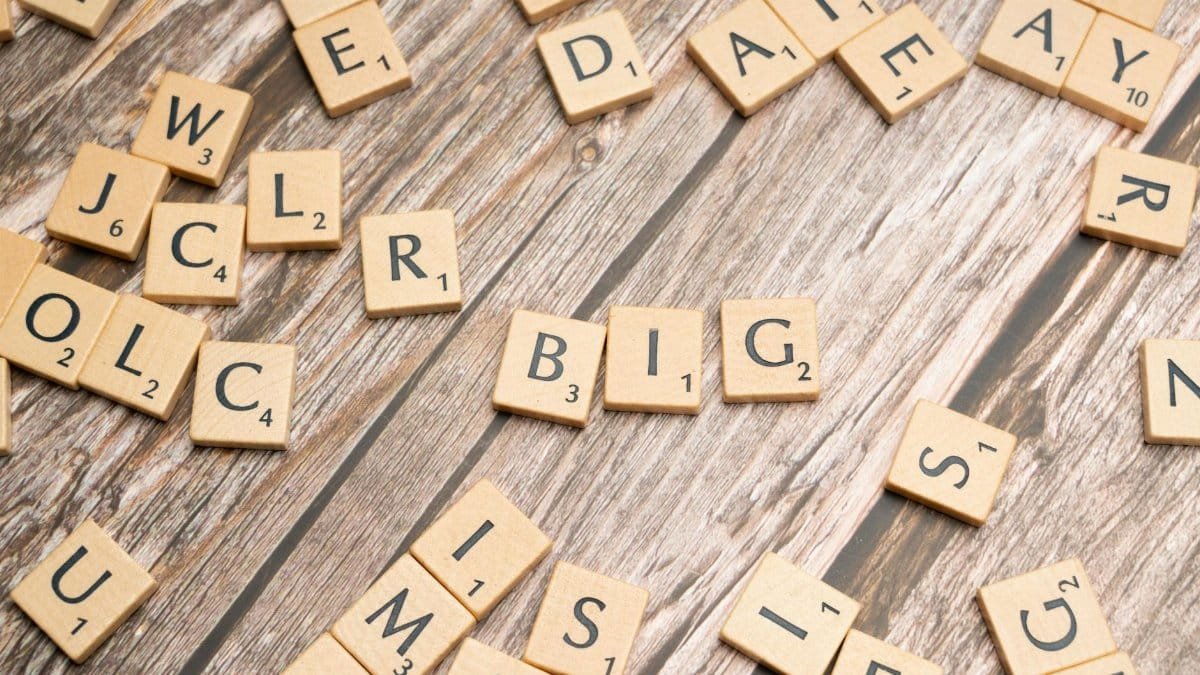 Scattered wooden letter tiles on a textured wooden table surface for creative word play.