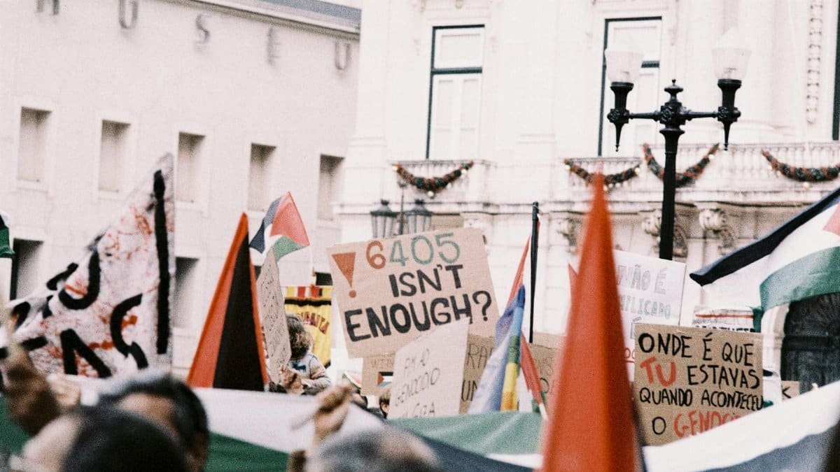 A vibrant protest in Lisbon features diverse signs and flags advocating for change.