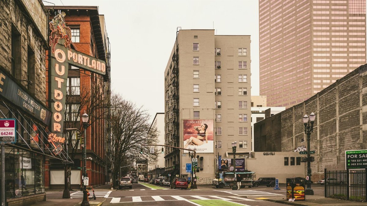 Urban street scene in downtown Portland featuring historic neon sign and modern architecture.
