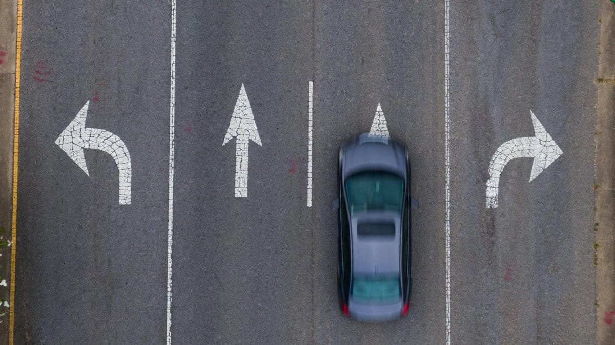 Top-down view of a moving car on a road with directional arrows, emphasizing urban transportation.