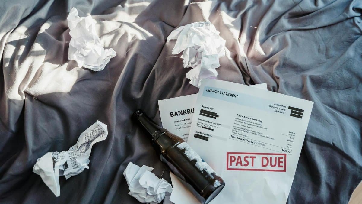 Scene of financial distress with bankruptcy notice, past due bills, and crumpled papers on a bed.