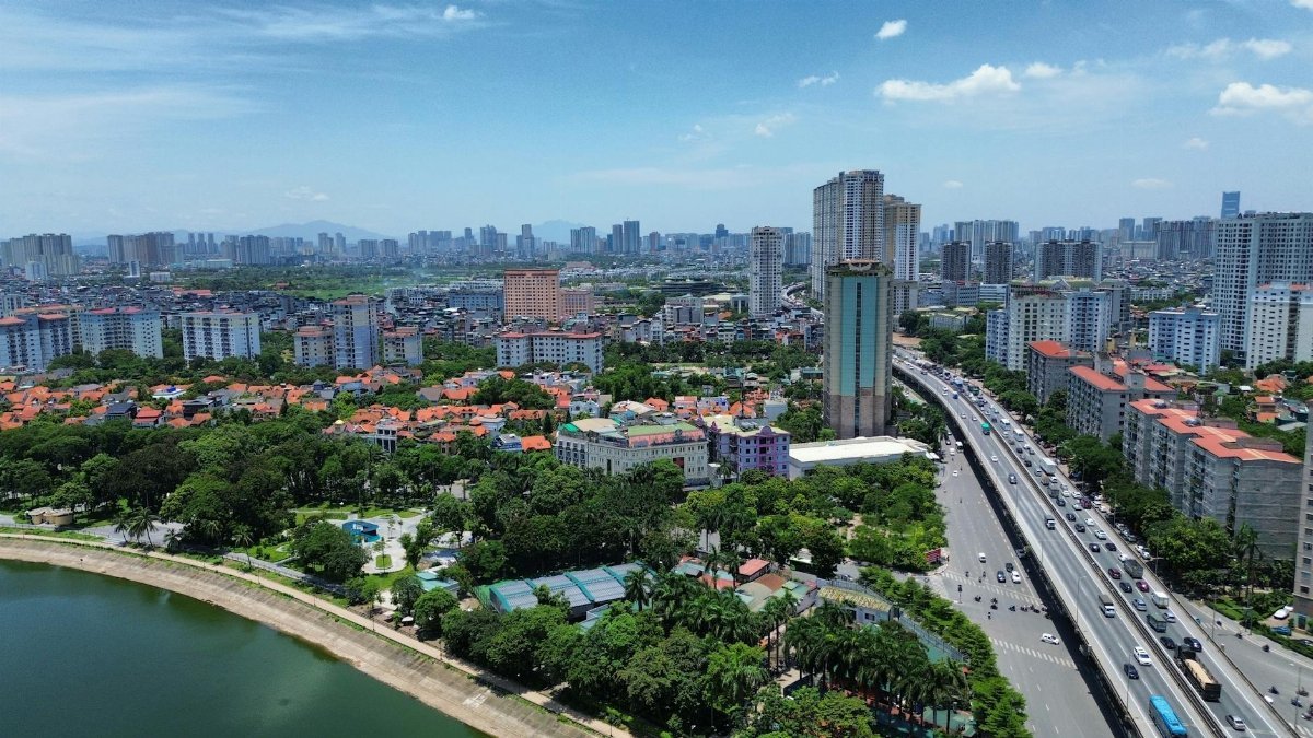 Expansive aerial view of Hanoi's urban skyline featuring residential areas, greenery, and clear blue skies.