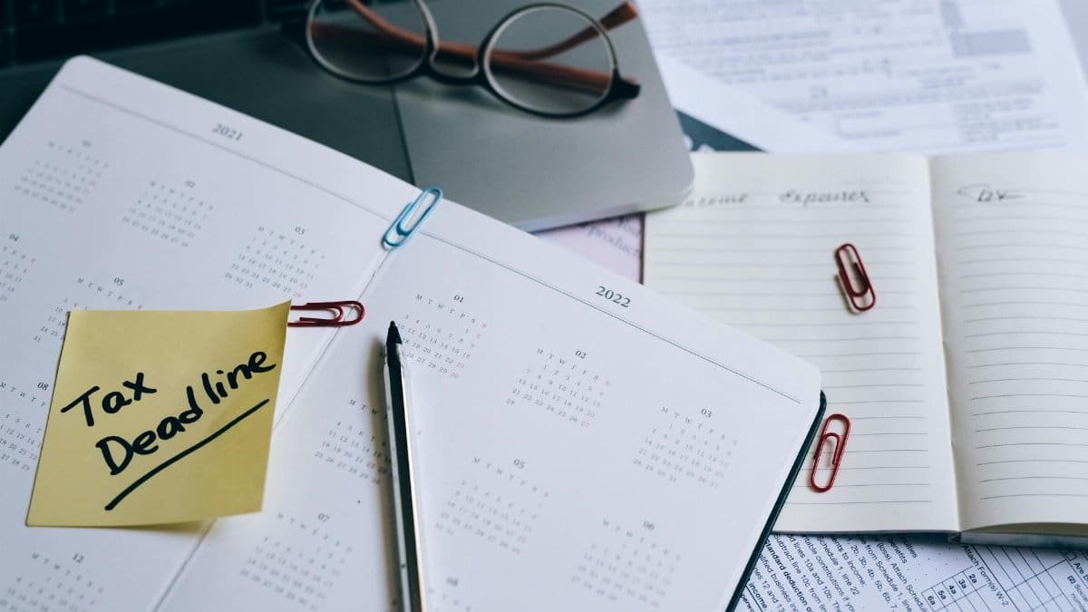 A desk with a planner, sticky note marked 'Tax Deadline', and paperwork, indicating financial planning.