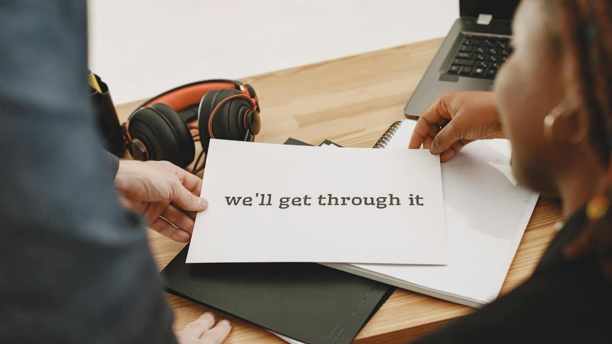 Hands holding a motivational note at a desk, symbolizing support and hope.