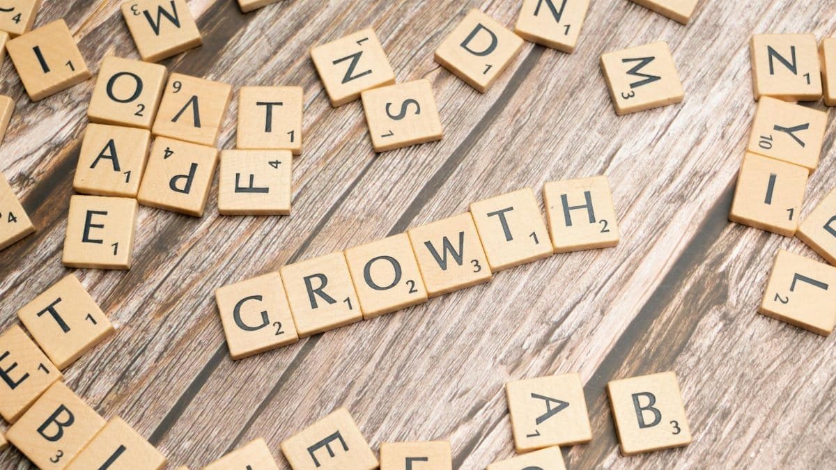 Scrabble tiles spelling 'growth' on a wooden surface symbolize progress and expansion.