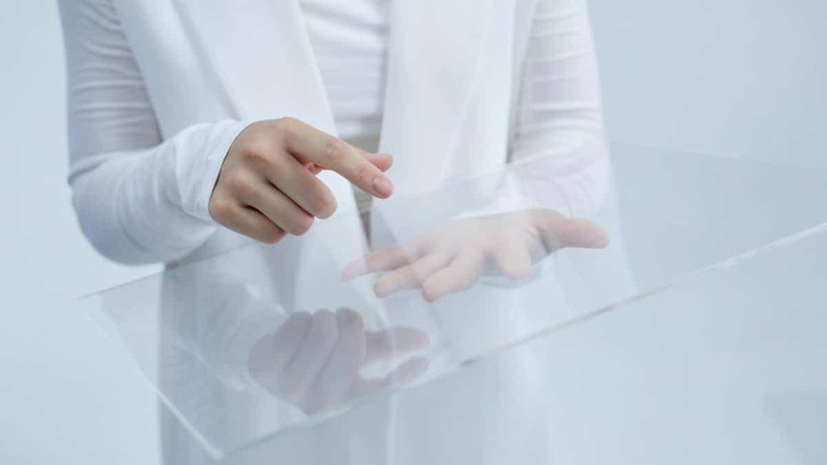 Person in white interacting with a clear glass interface, suggesting technological innovation.