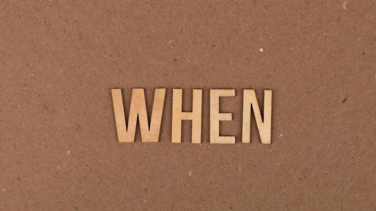 Wooden letters forming the word 'When' on a plain cardboard background.