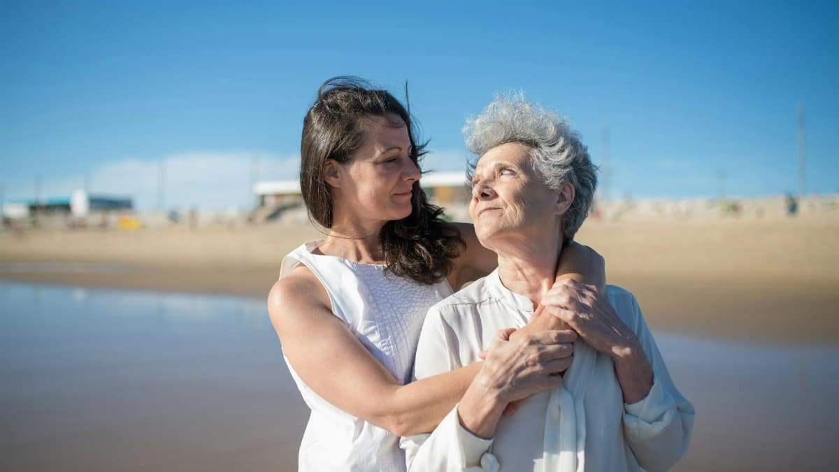 A loving embrace between a mother and daughter on a sunny beach in Portugal.