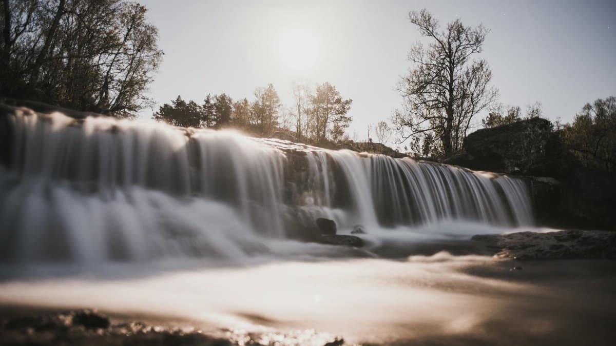 A tranquil waterfall in Rogaland, Norway, captured at sunset with smooth water effects.