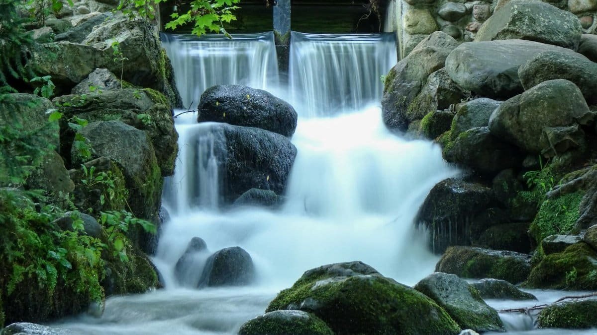 Beautiful long exposure shot of a waterfall surrounded by mossy boulders in Gdańsk, Poland.