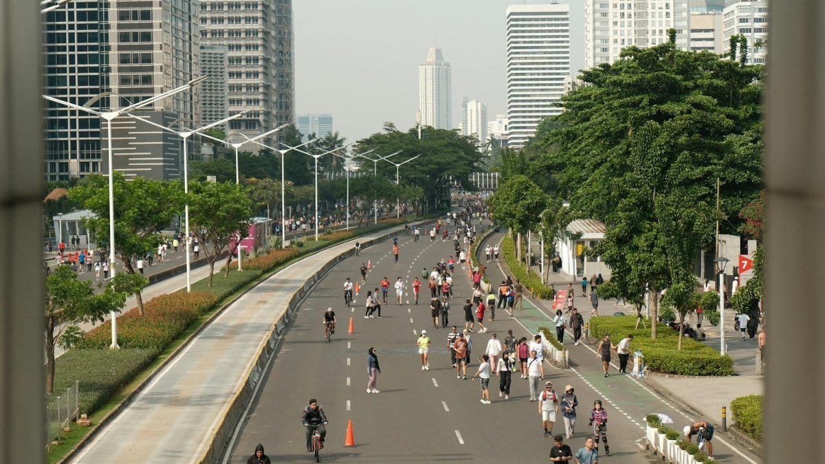 People enjoying a car-free street in a vibrant city setting, ideal for leisurely activities.