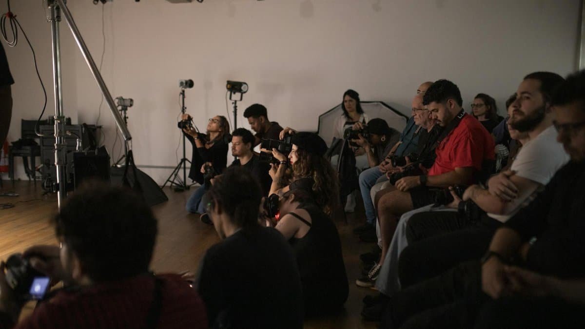 A group of photographers attentively engaged in a photography workshop indoors.