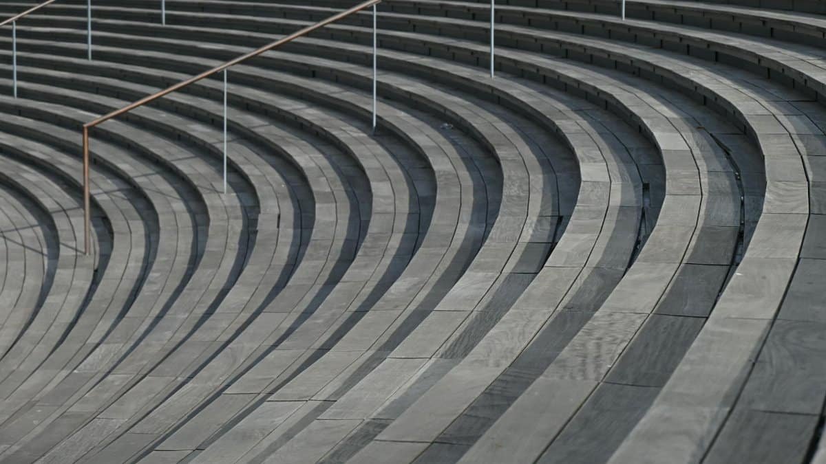 Minimalist view of curved concrete steps with metal railings, showcasing architectural design.