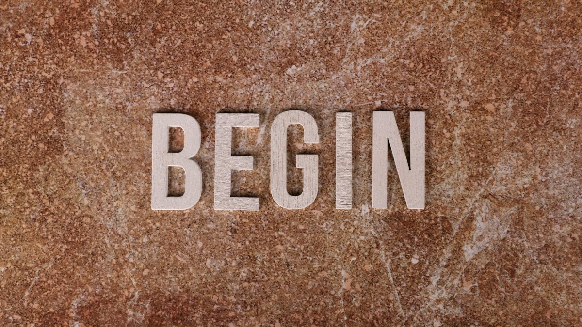 Text 'BEGIN' on a textured stone background, symbolizing a fresh start.