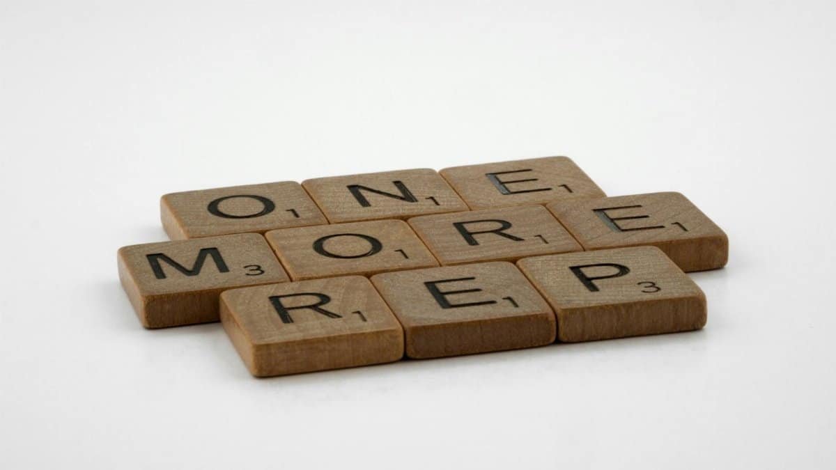 Scrabble tiles arranged to spell 'ONE MORE REP' on a clean white background.