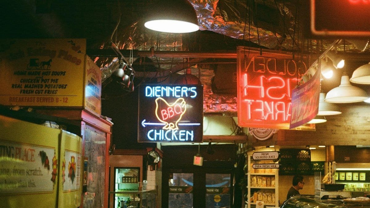 Vibrant neon signs illuminate a bustling Philadelphia market showcasing local cuisine.