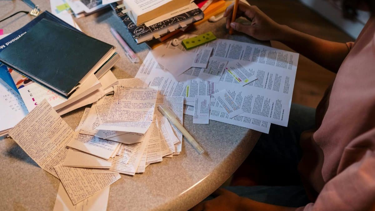 A student organizes notes and books in preparation for an exam, focusing on study materials.