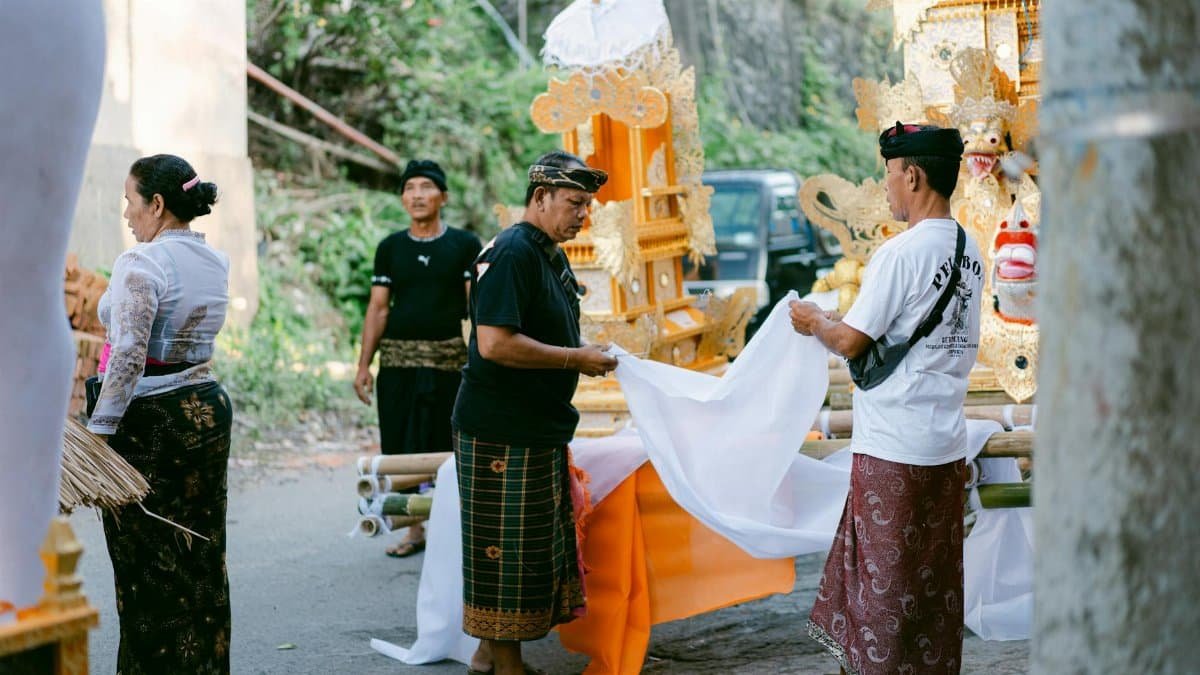 People preparing for a traditional Balinese ceremony outdoors, featuring elaborate decorations and attire.