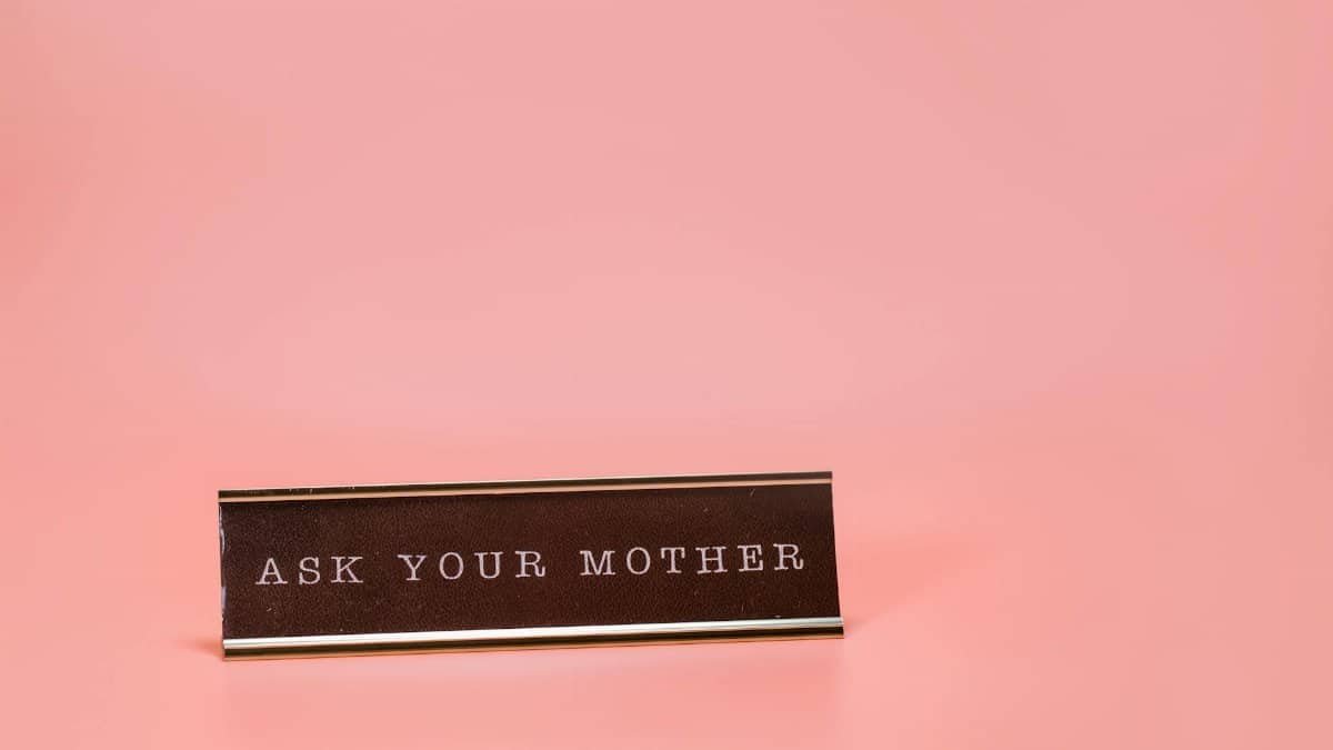 Humorous desk sign with 'Ask Your Mother' text on a pink backdrop.