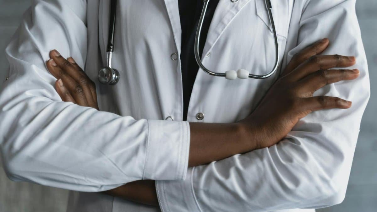 Close-up of a confident doctor in a lab coat standing with crossed arms and stethoscope.